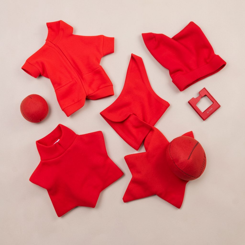 Overhead flat-lay photograph of a little star sports doll set with a sporty top, shorts, sneakers, and a small ball arranged on a fresh mint and white background, bright and energetic in mood.